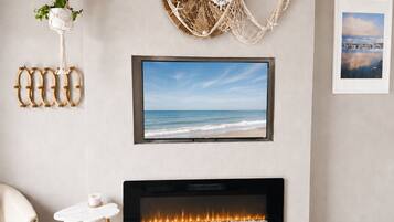 A living room with a flat-screen TV mounted above a fireplace, a wall-mounted decorative item, and a framed picture.