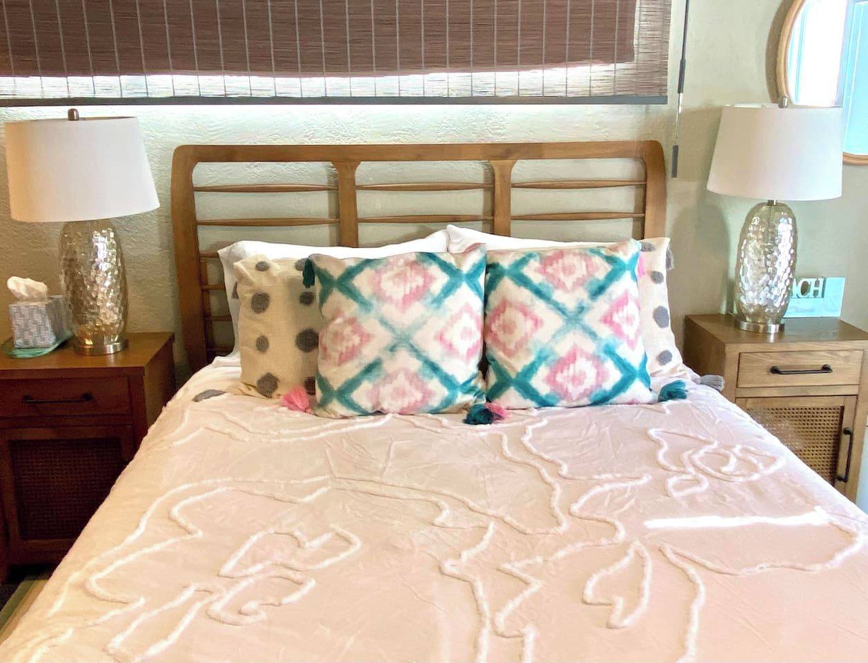 A bed with patterned bedding, two bedside lamps, and a wooden headboard.