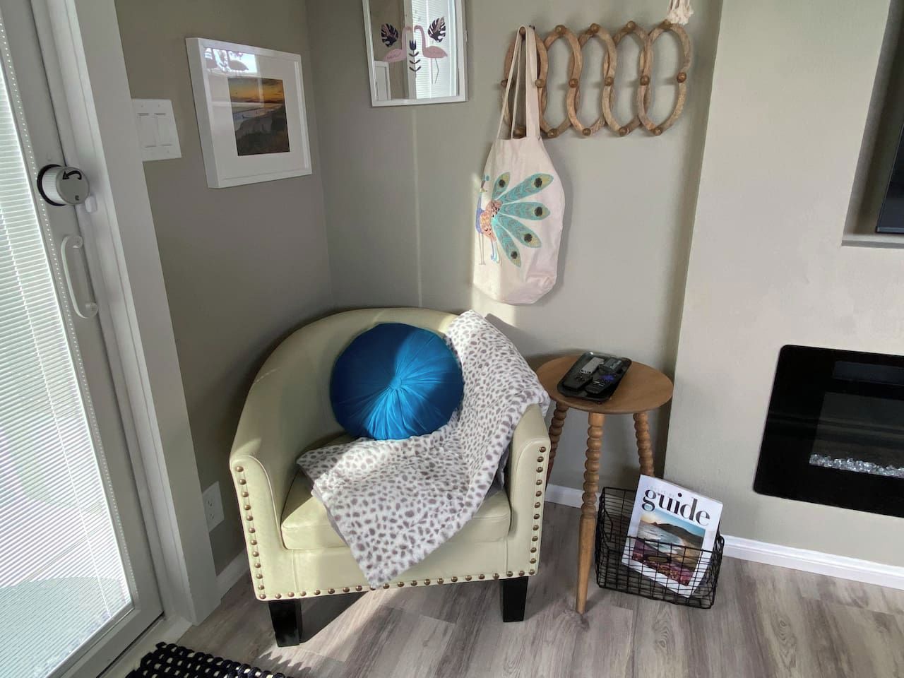 A room with a chair, a small table, a magazine, and wall decorations.