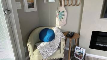 A room with a chair, a small table, a magazine, and wall decorations.