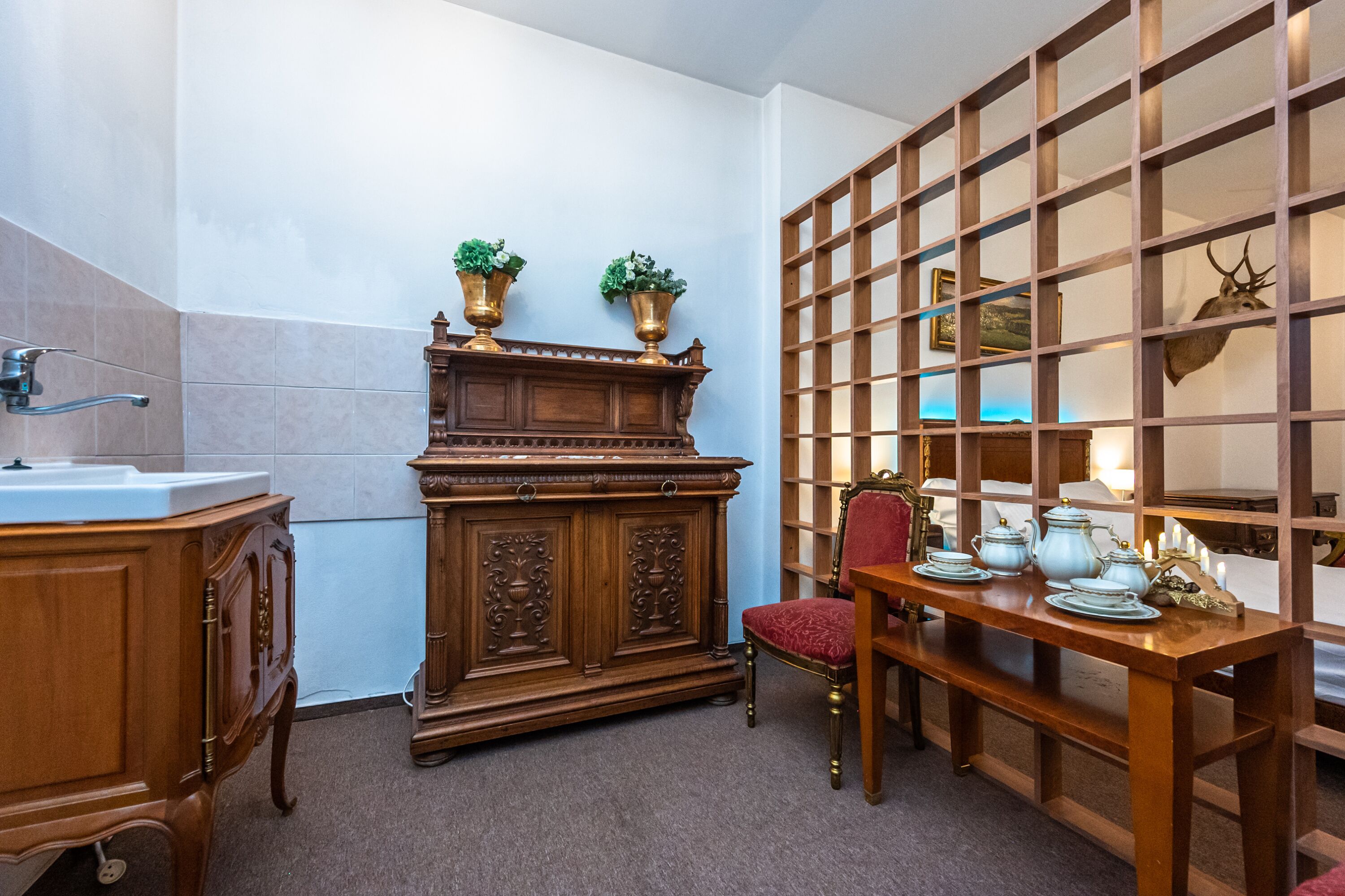Quarto tradicional com um armário de madeira, uma cadeira vermelha e uma mesa com jogos de chá.