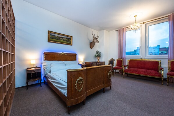 Une chambre à coucher avec un lit en bois, un canapé rouge, un lustre et une tête de cerf accrochée au mur.