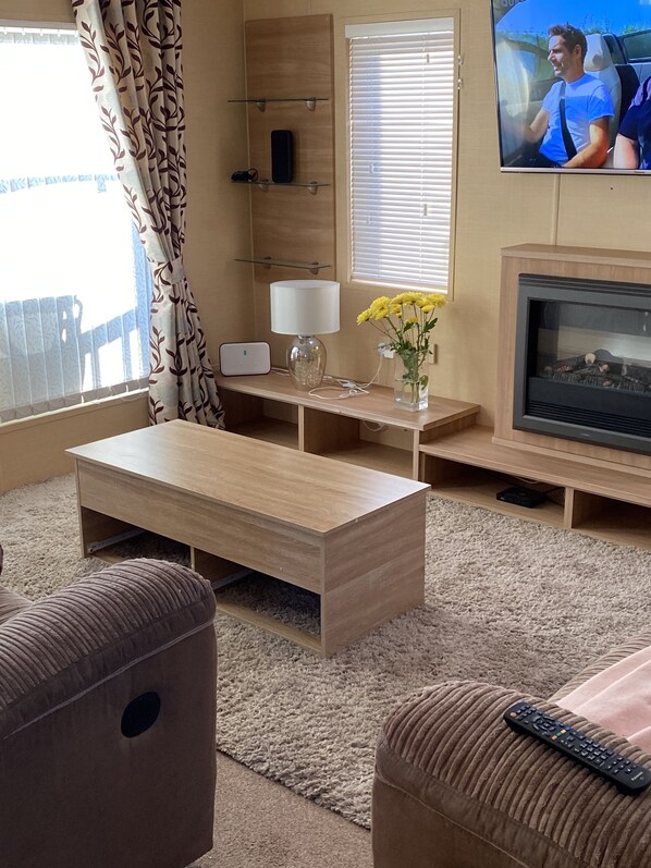 Una sala de estar con una mesa de centro de madera, un sofá, un televisor y una chimenea.