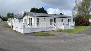 A single-story mobile home with a covered porch and a small staircase leading to the entrance. - Luxury Air Conditioned holiday Lodge . sleeps 5  Burgh Castle  Great Yarmouth (Burgh Castle)