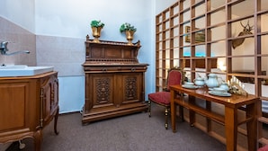 A traditional room with a wooden cabinet, a red chair, and a table with tea sets. - Family apartment 12 (Hlavní mesto Praha)