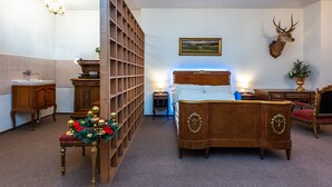 A bedroom with a wooden bed, a mounted deer head, a bookshelf, a chandelier, and a painting on the wall. - Family apartment 12 (Hlavní mesto Praha)