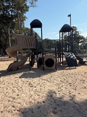 A playground with a slide, climbing structures, and a tunnel.