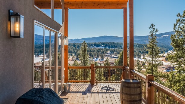 Une terrasse en bois offrant une vue sur un paysage montagneux.