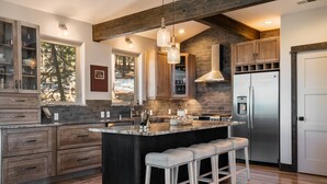 Une cuisine moderne dotée d’un grand îlot central, de meubles en bois et d’un réfrigérateur en acier inoxydable.