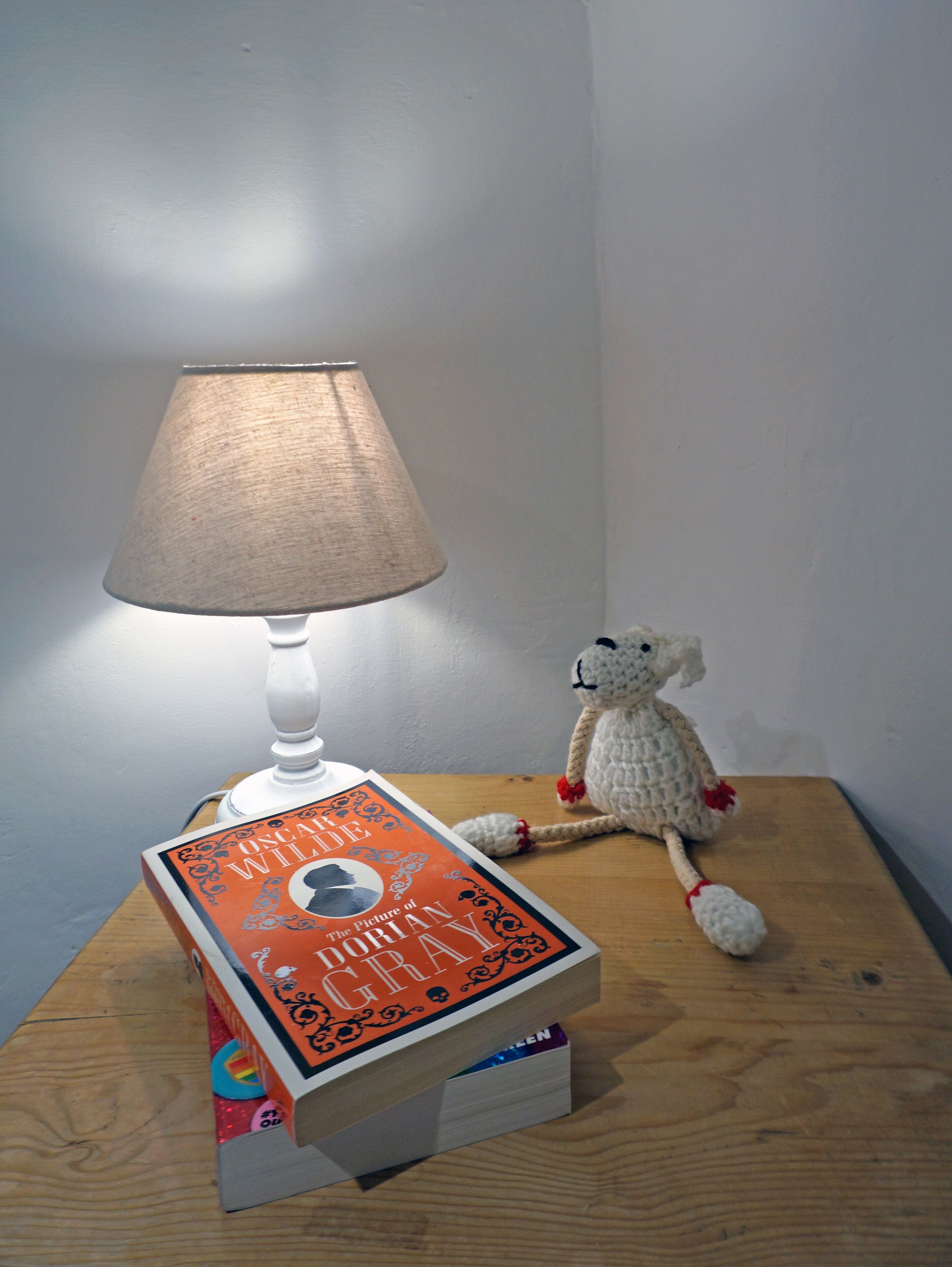 A lamp, a book, and a stuffed toy on a wooden surface.