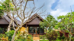 Ein Haus mit überdachter Veranda, umgeben von einem gepflegten Garten mit verschiedenen Pflanzen und einem Kiesweg zum Eingang.