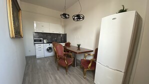 Une cuisine compacte comprenant un lave-linge, une table à manger avec des chaises et un réfrigérateur.