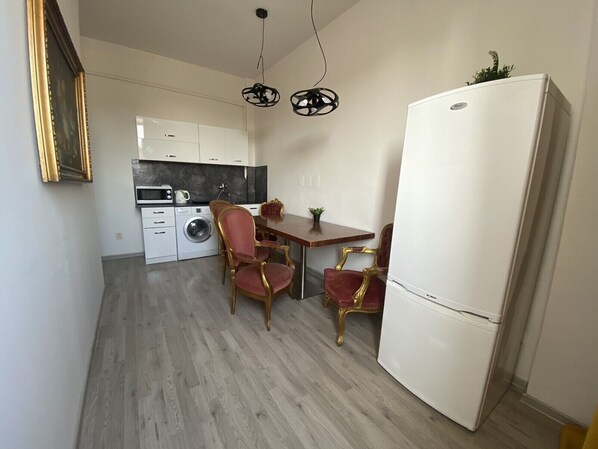 Eine kleine Küche mit Waschmaschine, Esstisch mit Stühlen und Kühlschrank.