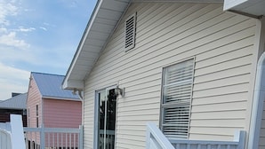 A house with a grey deck and white railings, a front door, and a window with blinds. - Blessed A-Shore-ance one short block to the beach with private back deck.  (Panama City Beach)