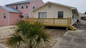 A two-story house with a wooden deck and a small palm tree in the front yard. - Blessed A-Shore-ance one short block to the beach with private back deck.  (Panama City Beach)