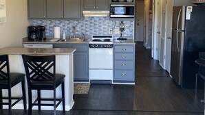 A modern kitchen with grey cabinets, a white stove, and a black refrigerator.