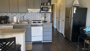 A kitchen with grey cabinets, a stainless steel refrigerator, a microwave, and a stove.