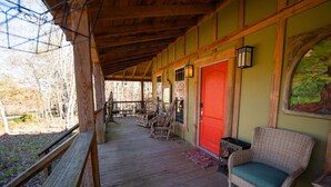 Un portico coperto con pavimento in legno, mobili in vimini e una porta rossa.