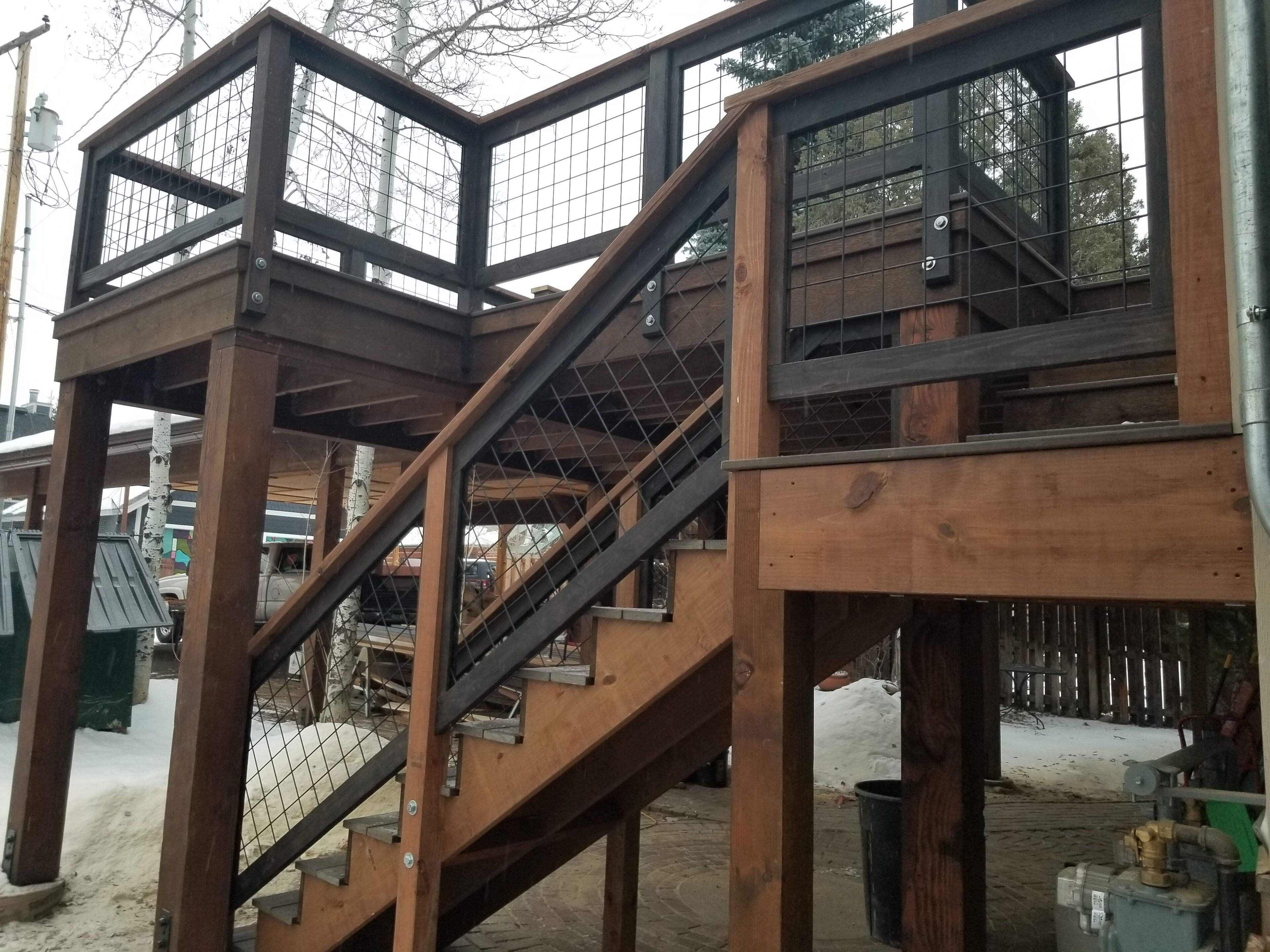 Eine Holztreppe mit Metallgeländern, die zu einer überdachten oberen Ebene führt.