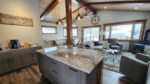 A spacious living area with a large island, wooden beams, and a clock on the wall. - Newly remodeled Old town/2 King Suites
Pet Friendly
Deck/Grill
EV/Carport (Steamboat Springs)