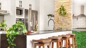 A modern kitchen with stainless steel appliances, a stone accent wall, and a green wall garden.