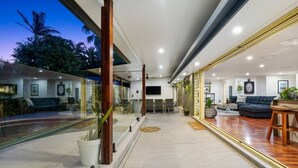 A modern interior with a glass wall, wooden beams, and a seating area with a sofa and coffee table.