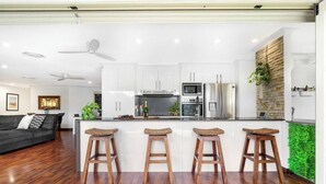 A modern kitchen with white cabinets, stainless steel appliances, and three wooden stools.