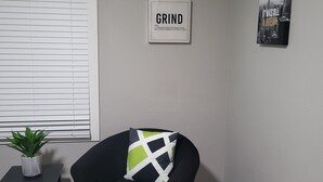 Ett vardagsrum med en svart fåtölj, ett litet bord med en växt och ett inramat, inspirerande citat på väggen.