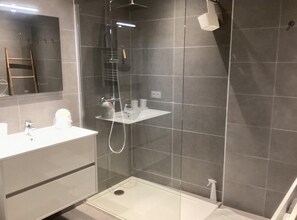Ein modernes Badezimmer mit einer Duschkabine, einem weißen Waschtisch und einem Handtuchhalter.