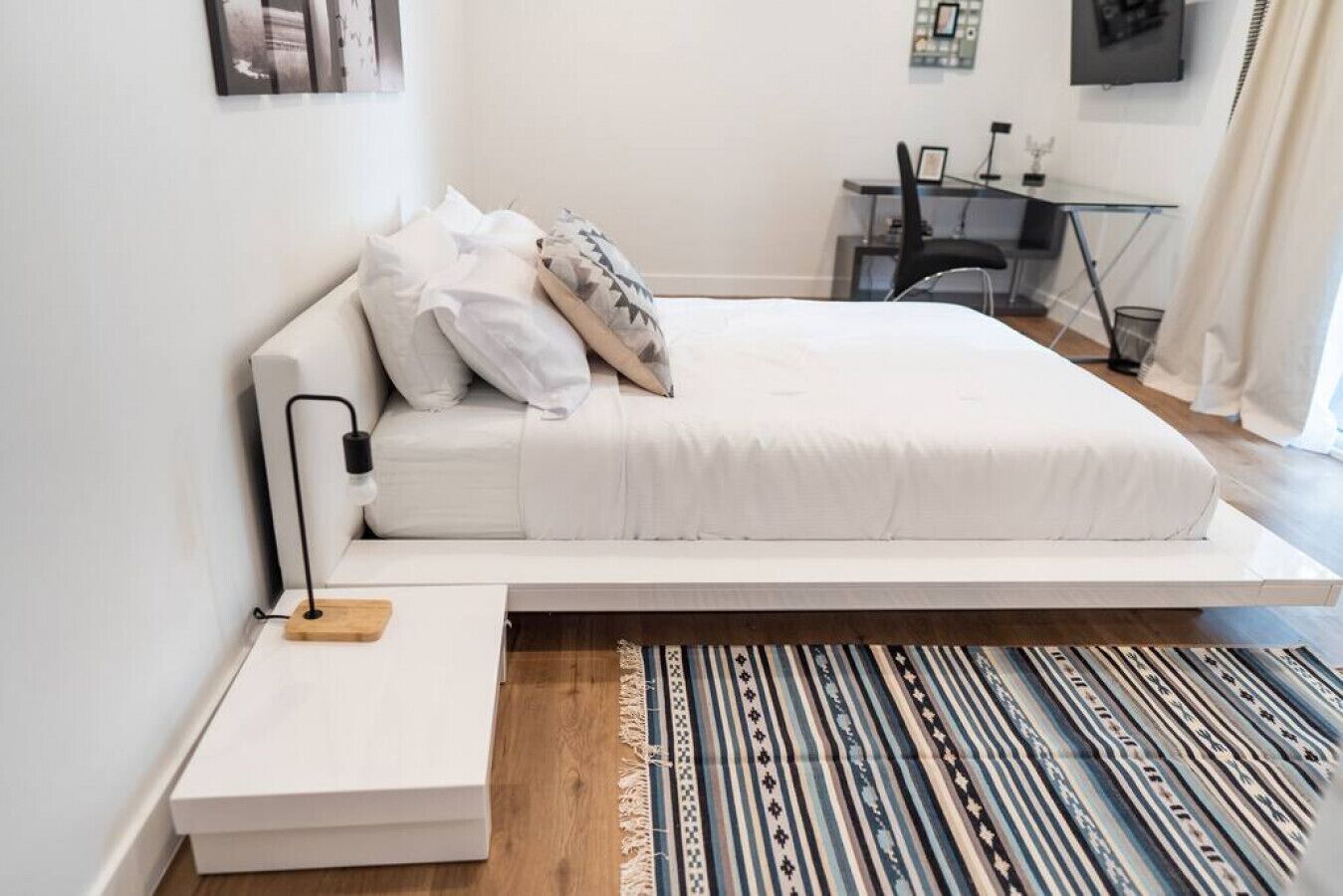 Un dormitorio moderno con cama, mesita de noche y escritorio con silla.