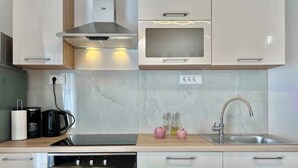 Una cocina moderna con horno integrado, cafetera y lavabo con grifo.