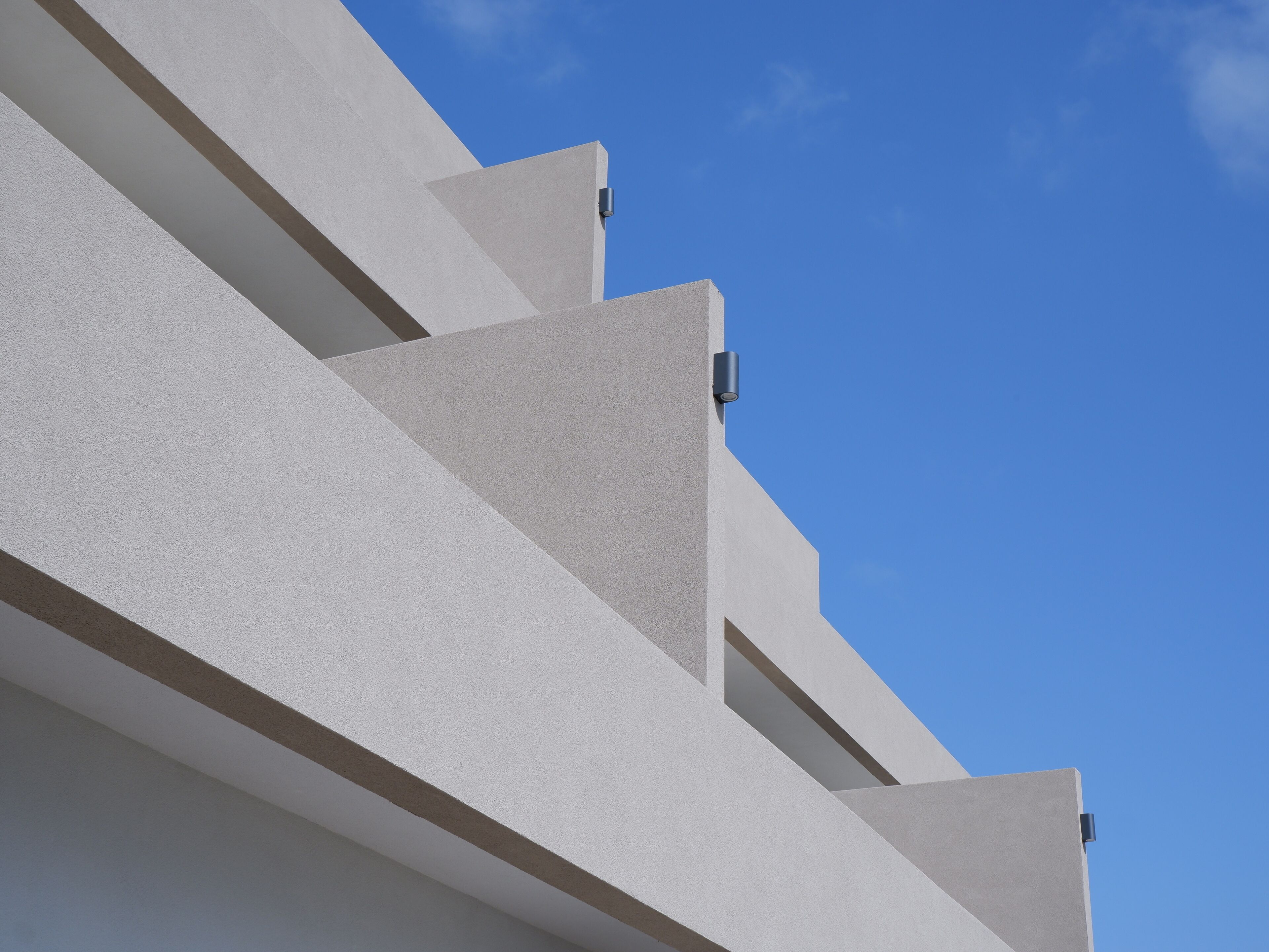 Un edificio moderno con fachada geométrica y cielo azul despejado al fondo.