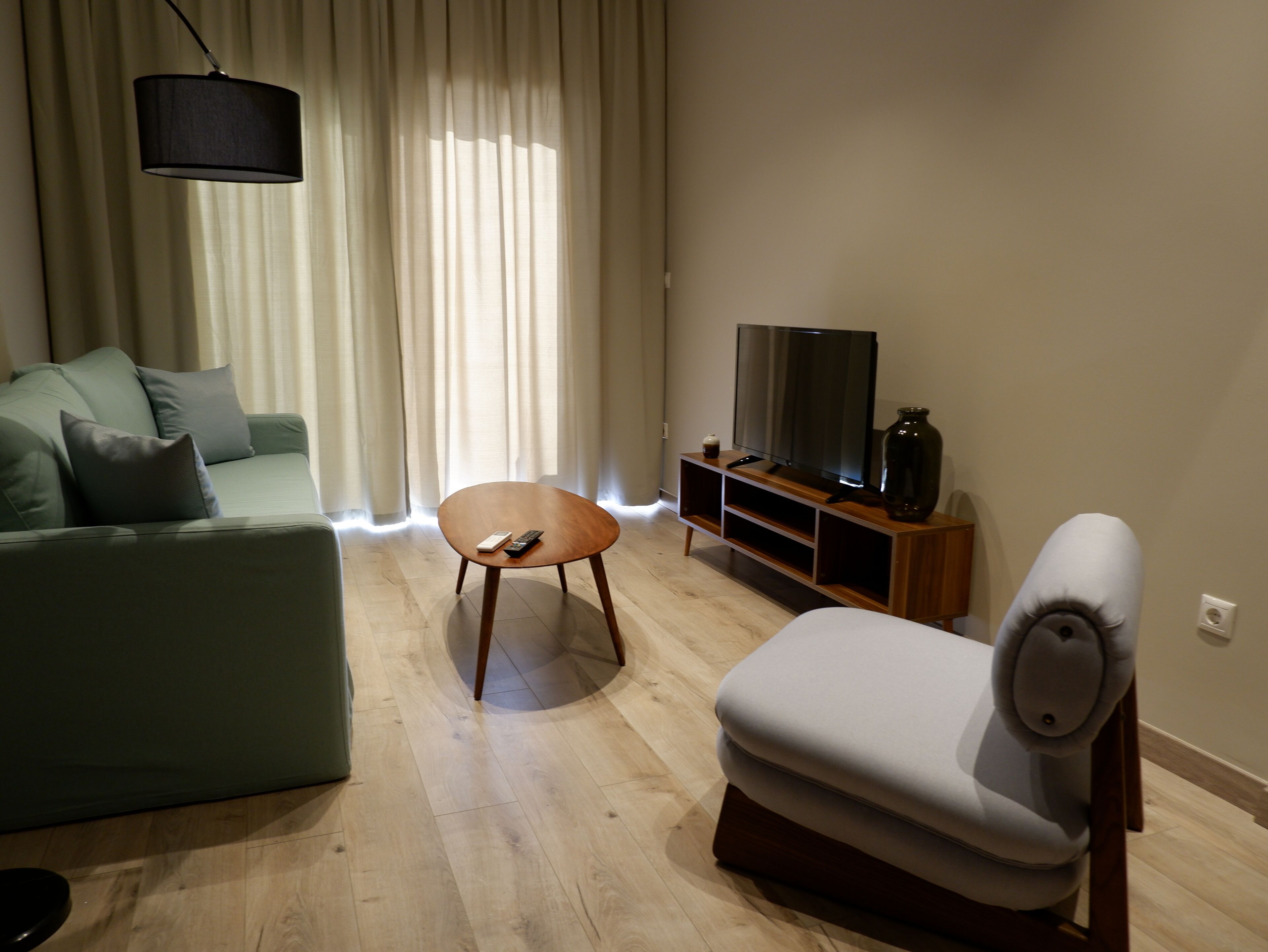 Un salon moderne comprenant un canapé, une petite table ronde, un meuble pour la télévision et un fauteuil.