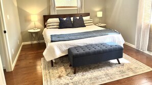 A bedroom with a large bed, bedside lamps, a window with curtains, and a rug. - This House Got RIZZ - Recently Renovated Lake Thompson Canal Home (Howell)