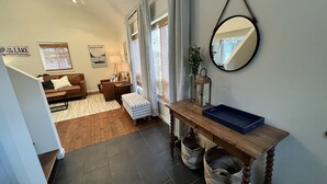 A living room with a sofa, a coffee table, and a mirror. There is a window with curtains and a sign on the wall. - This House Got RIZZ - Recently Renovated Lake Thompson Canal Home (Howell)