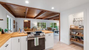 Una cocina moderna con vigas de madera, una isla grande y un comedor con vistas a los árboles.