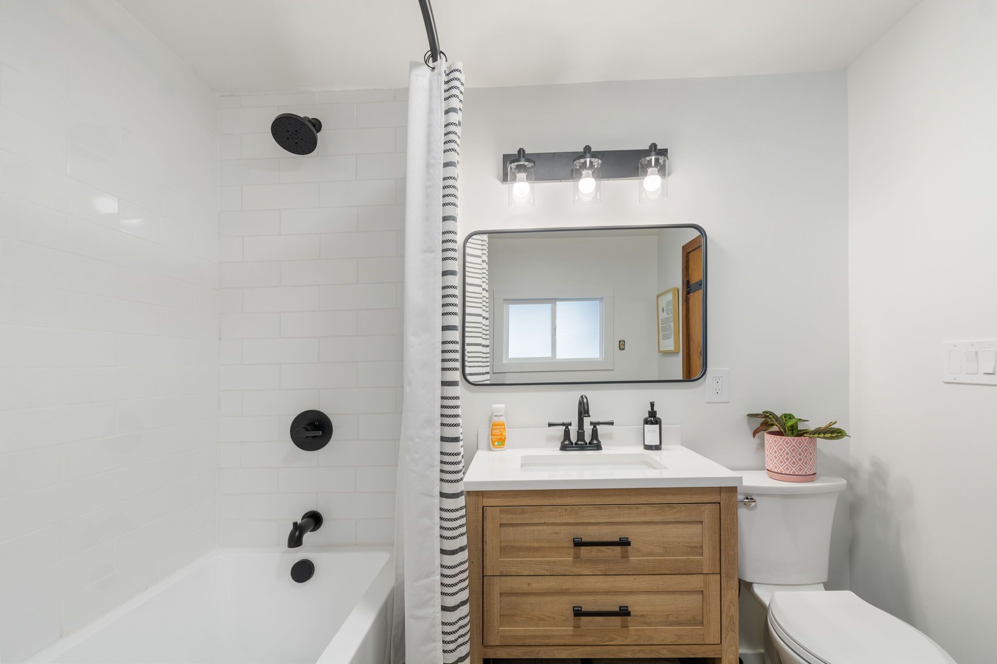 A modern bathroom with a shower, toilet, sink, and vanity.