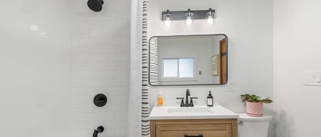 A modern bathroom with a shower, toilet, sink, and vanity.