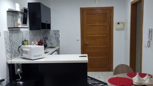A compact kitchen with a white countertop, black cabinets, and a wooden door. - APPART CENTRAL LAC 2 T.H.STANDING (Les berges du lac)