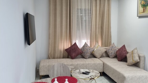 A modern living room with a sofa, coffee table, and red decorative items. - APPART CENTRAL LAC 2 T.H.STANDING (Les berges du lac)