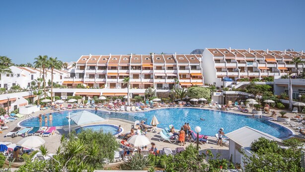Un hôtel doté de nombreux balcons, d’une piscine et de chaises longues.