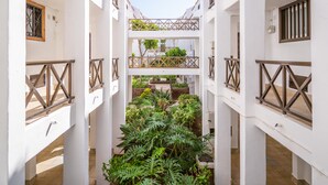 Une cour bordée de bâtiments blancs, de balustrades en bois et d’une végétation luxuriante.