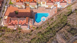 Vista aérea de um resort com vários edifícios, uma piscina grande e um estacionamento.