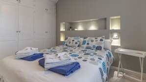 Quarto com cama, guarda-roupa e mesas de cabeceira.