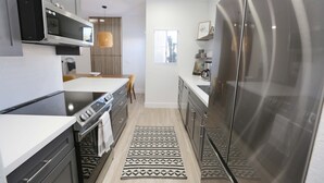 A modern kitchen with stainless steel appliances, a central island, and a patterned rug. - Mission Gorgeous - Complete Remodel (Scottsdale)