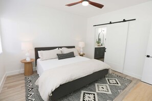 Ein Schlafzimmer mit Bett, Nachttischlampen, Deckenventilator, Teppich und Kleiderschrank.