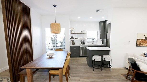 A modern kitchen with a central island, wooden dining table, and bar stools. - Mission Gorgeous - Complete Remodel (Scottsdale)