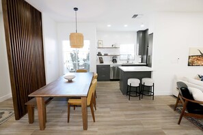 Eine moderne Küche mit einer zentralen Kochinsel, einem Holzespeisetisch und Barhocker.