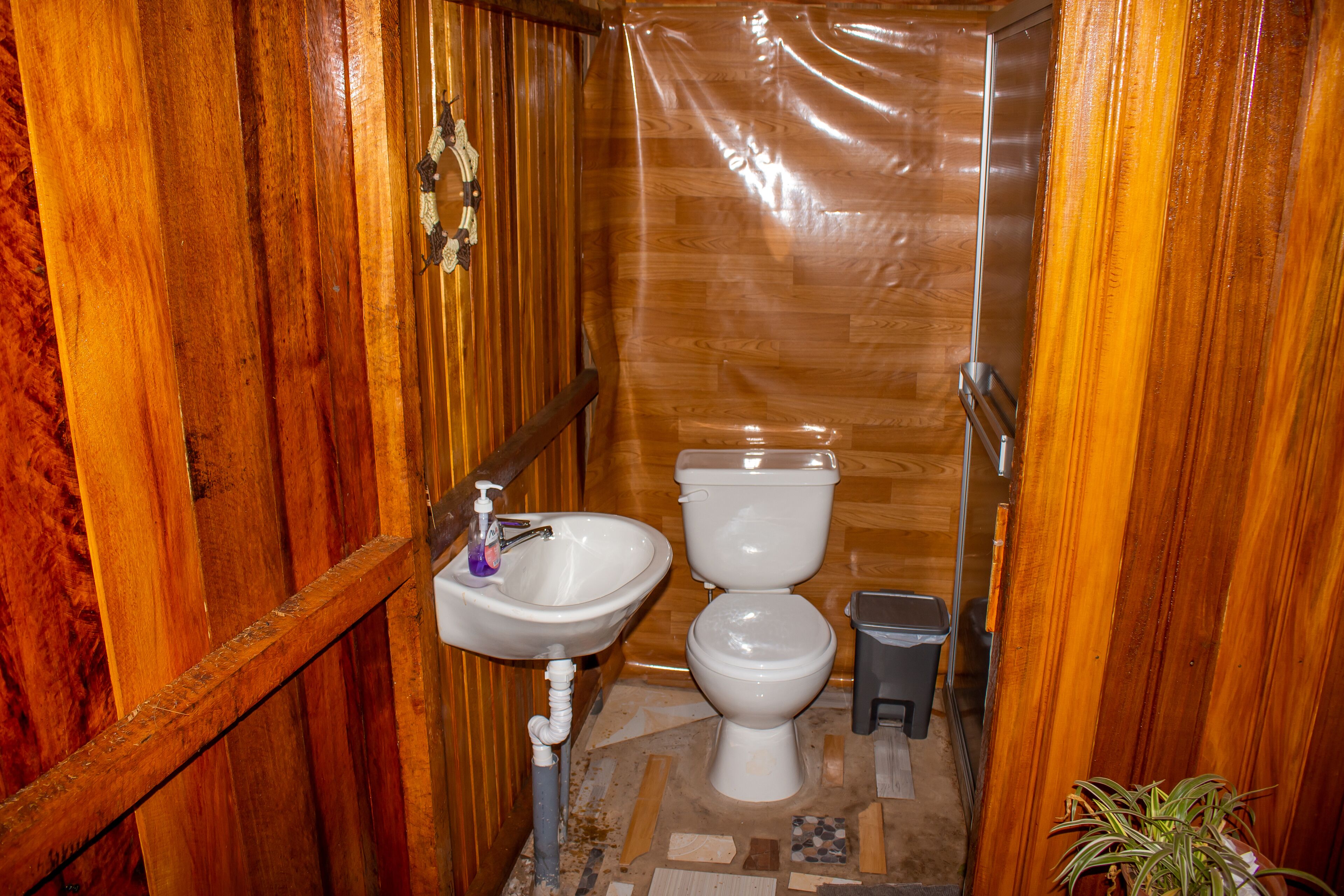 Un baño pequeño con paneles de madera, un lavamanos, un inodoro y un bote de basura.