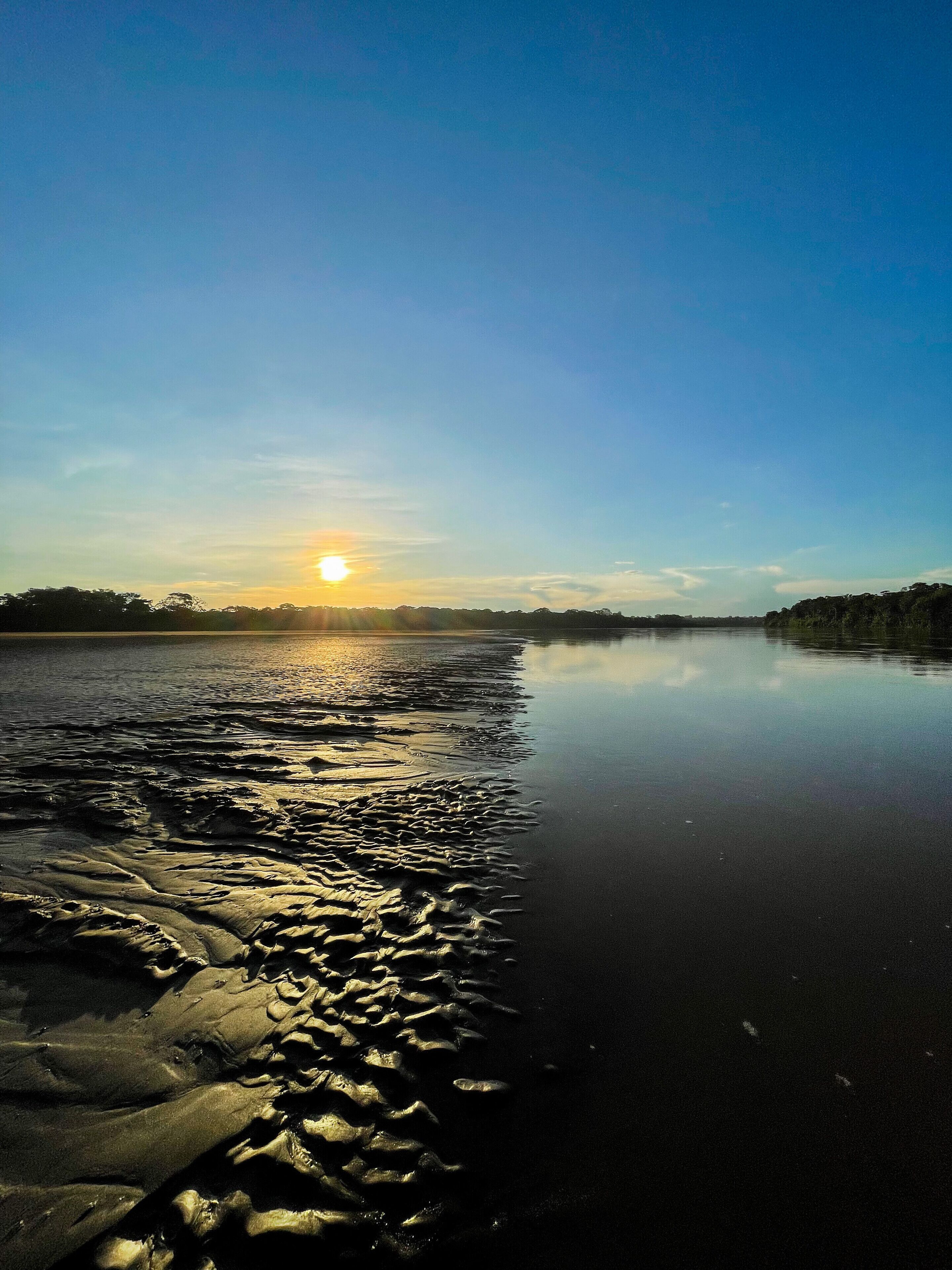 A calm river at sunset with a clear sky.